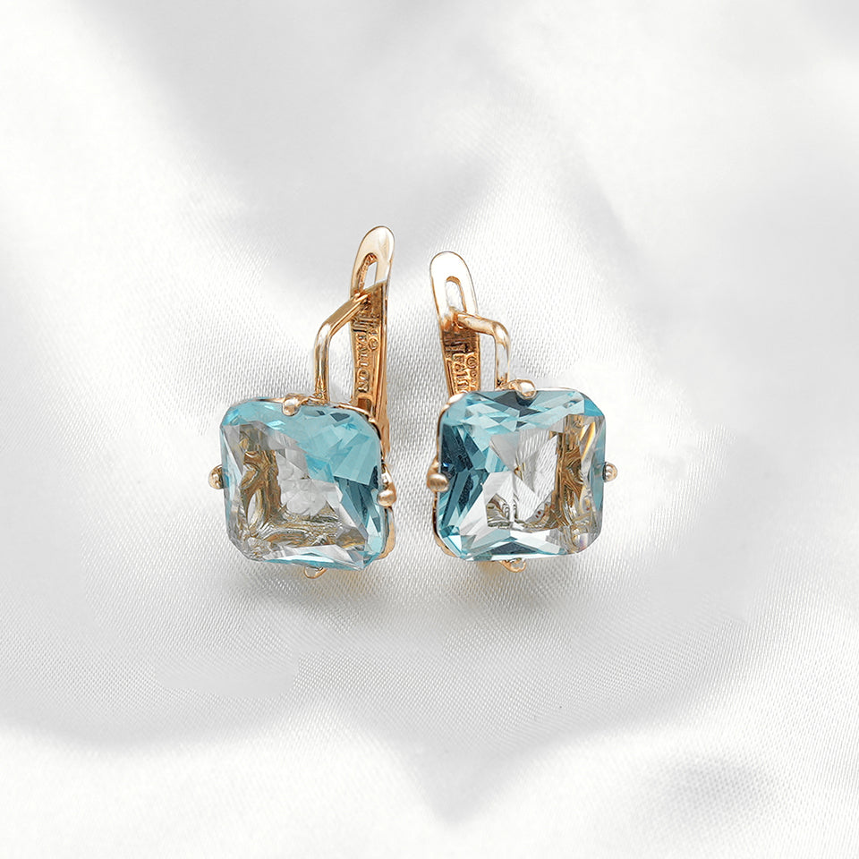 "Gold latch back earrings with cushion-cut light blue gemstones, elegant and reflective." Earrings (All Categories) from FJ Jewelry