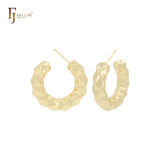 Aretes tipo aro con forma de C y textura de rombo en oro de 14 quilates, oro rosa y oro blanco.